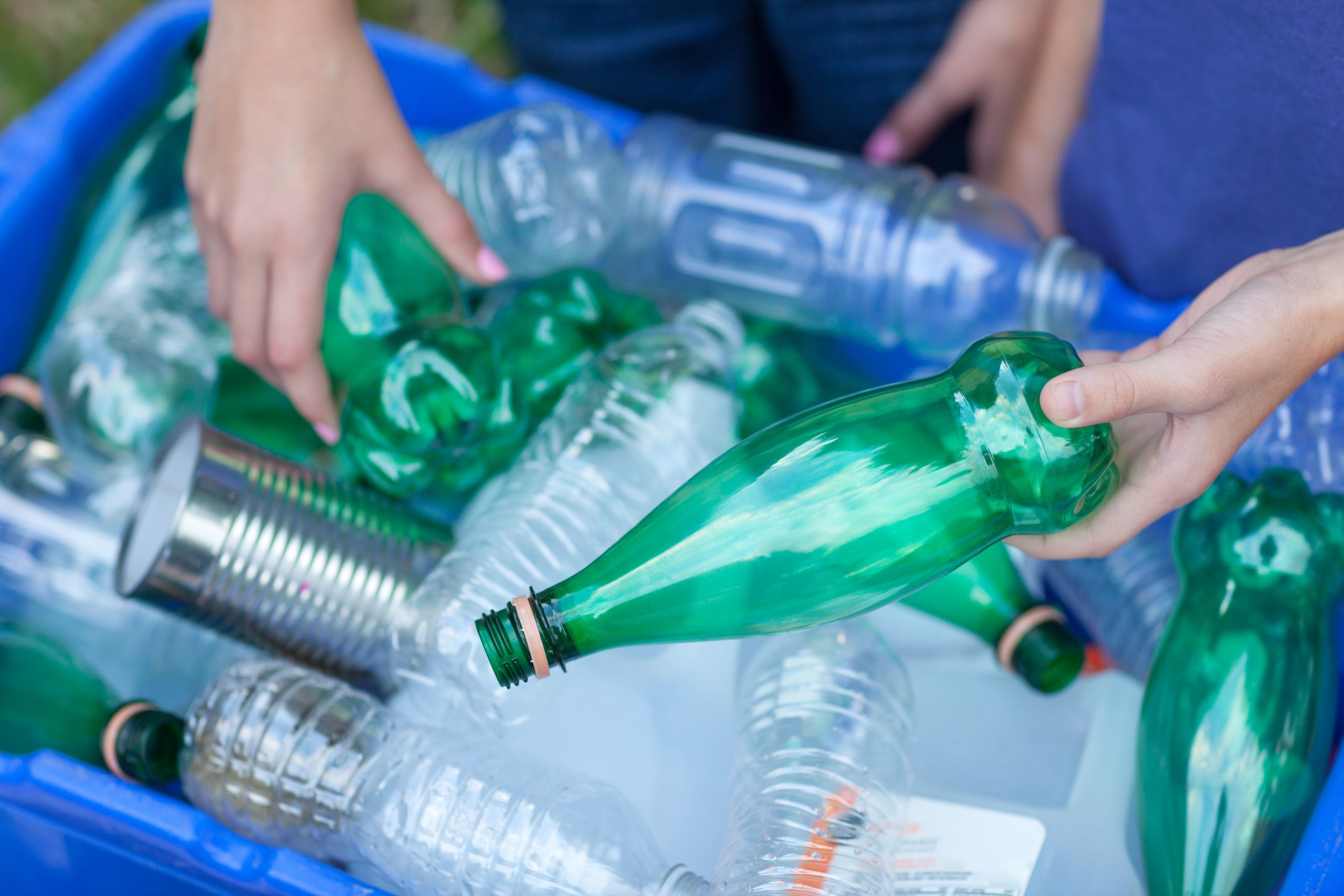 blue and green empty plastic bottles being held